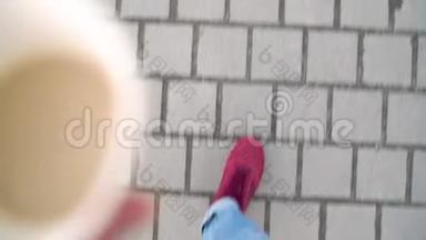 在人行道上行走的穿着红色运动鞋的男子腿的俯视图.. 男人走路喝咖啡